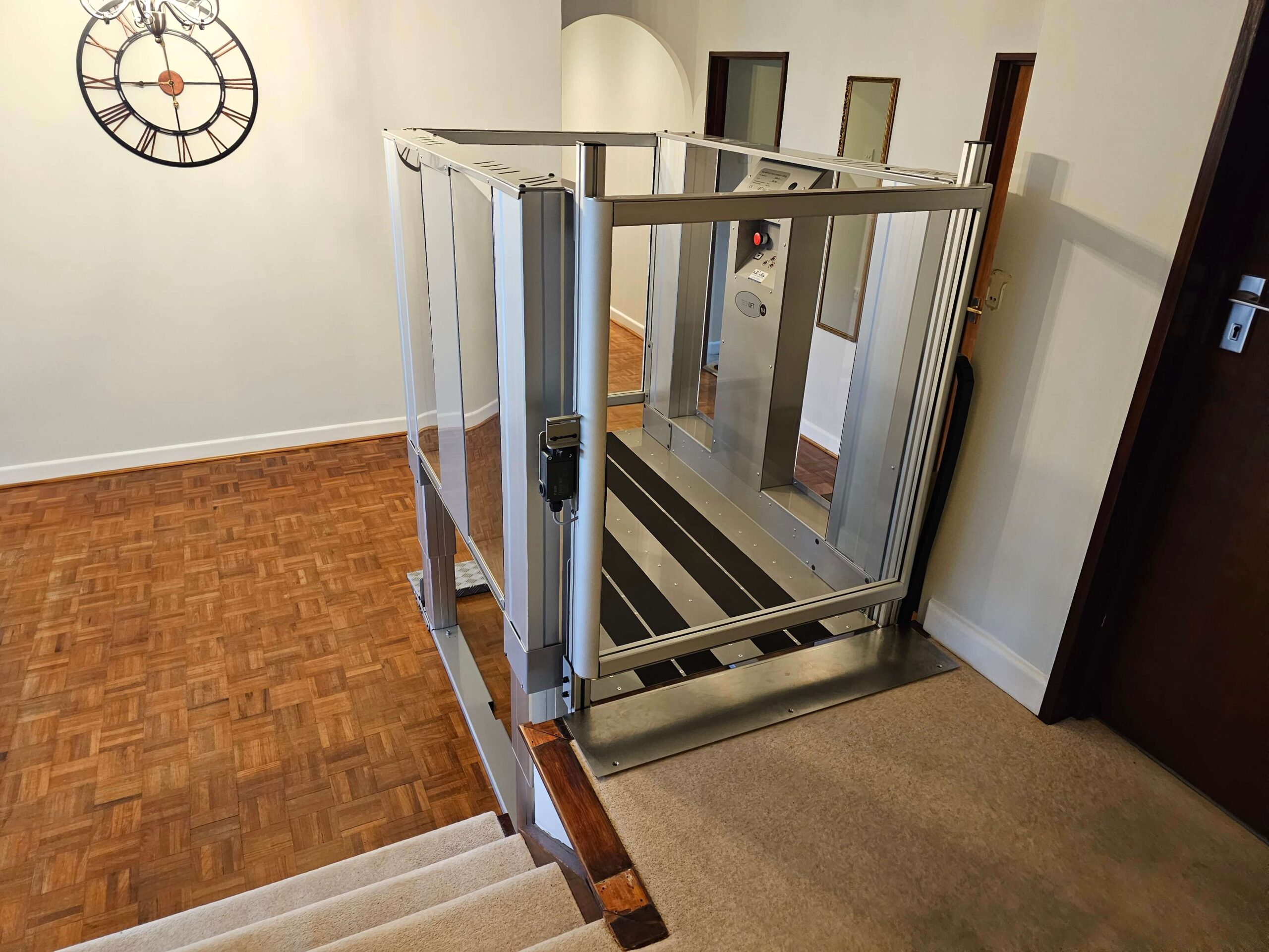 Clear glass door into a platform lift installed in hallway