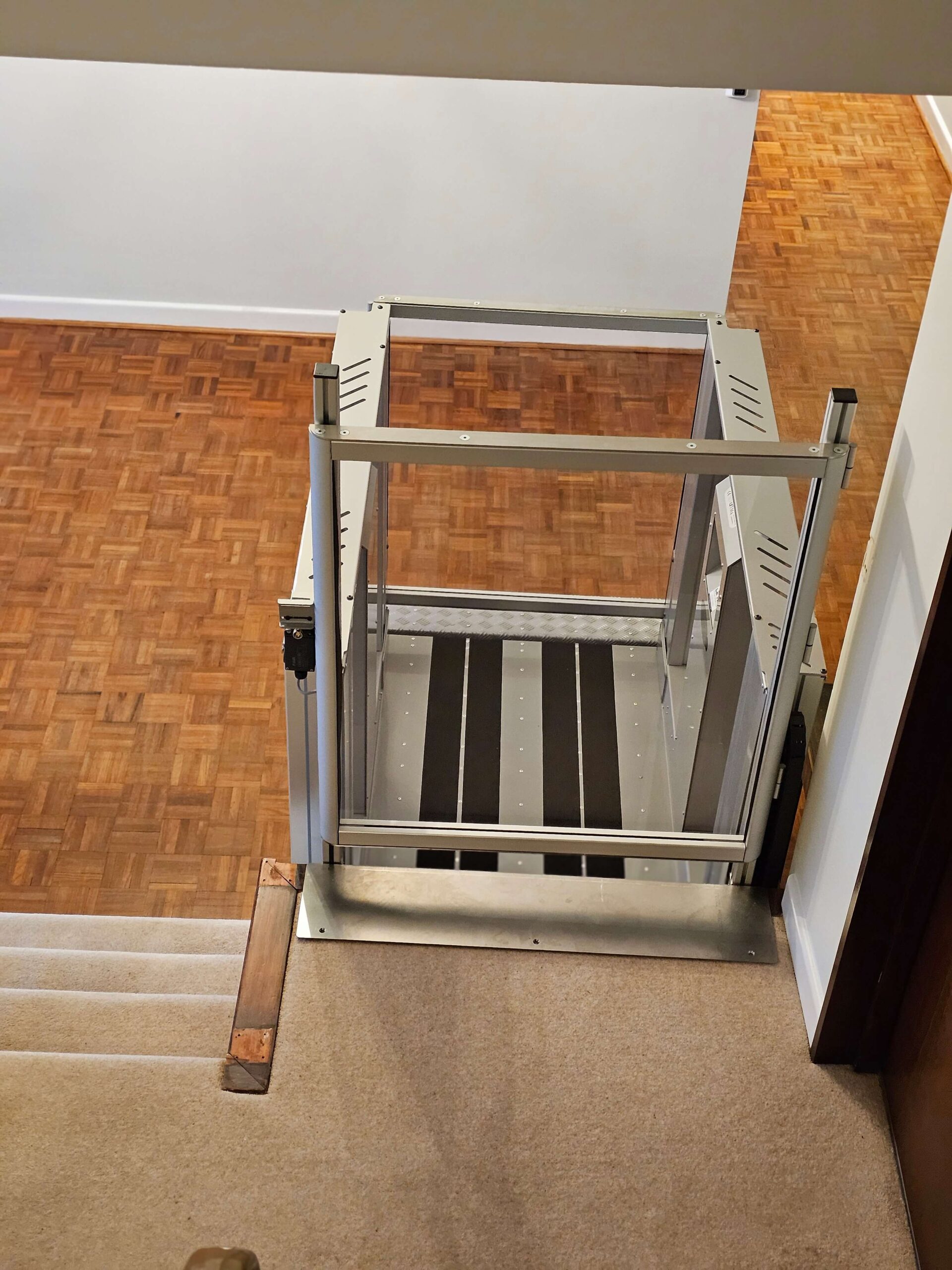 Step lift installed next to a caperted small flight of steps.