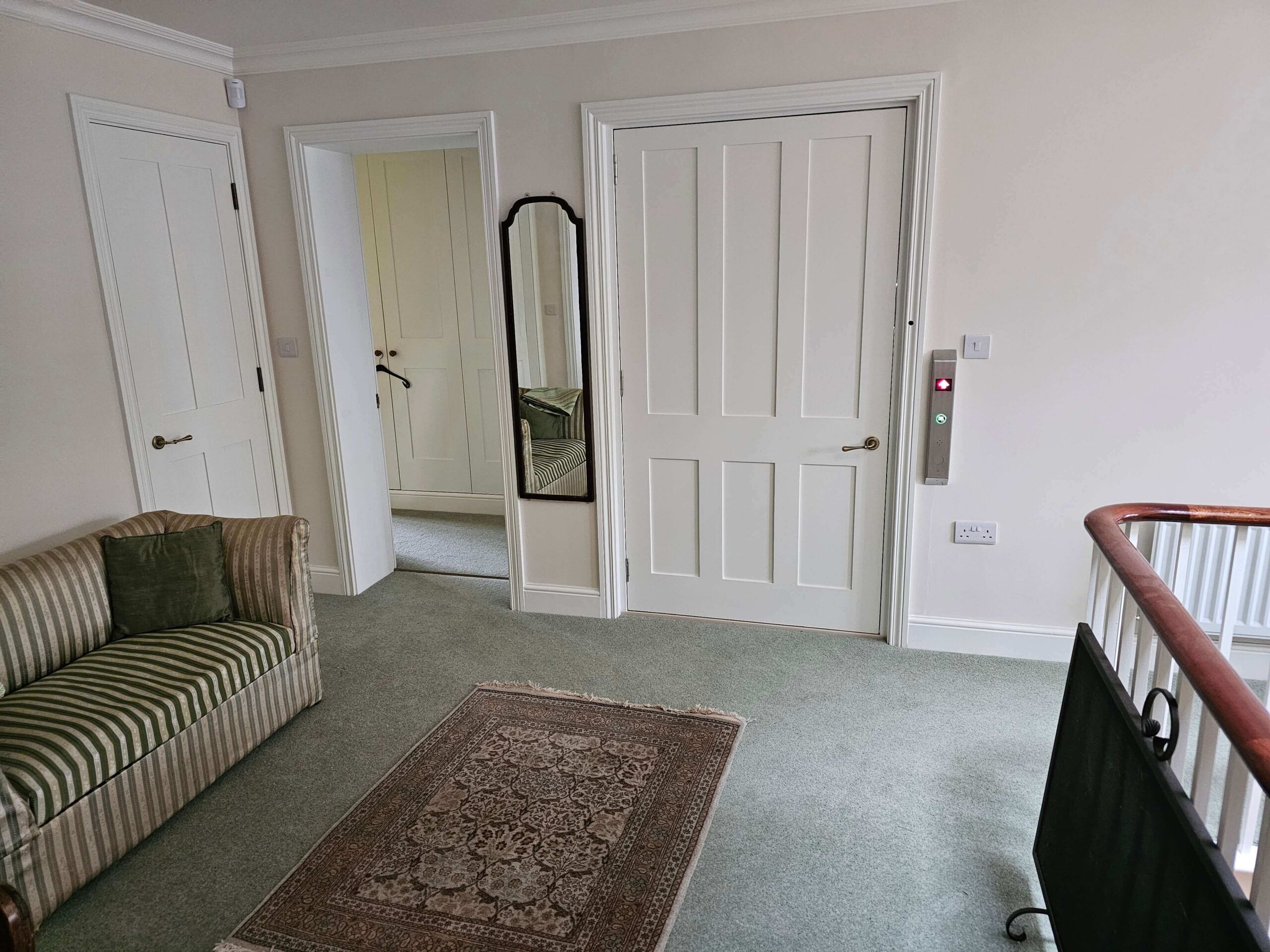 First floor landing showing the British Style home lift doors closed alongside other internal doors, with call panel mounted to the right of the door frame.