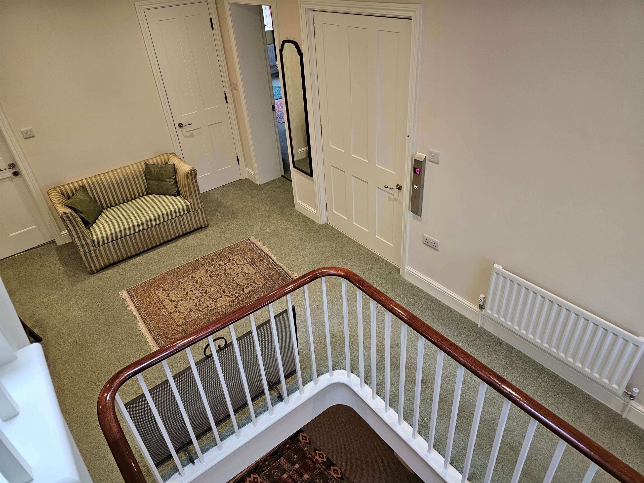 First floor landing with the British Style home lift door closed, showing the lift call panel to the right of the door frame.