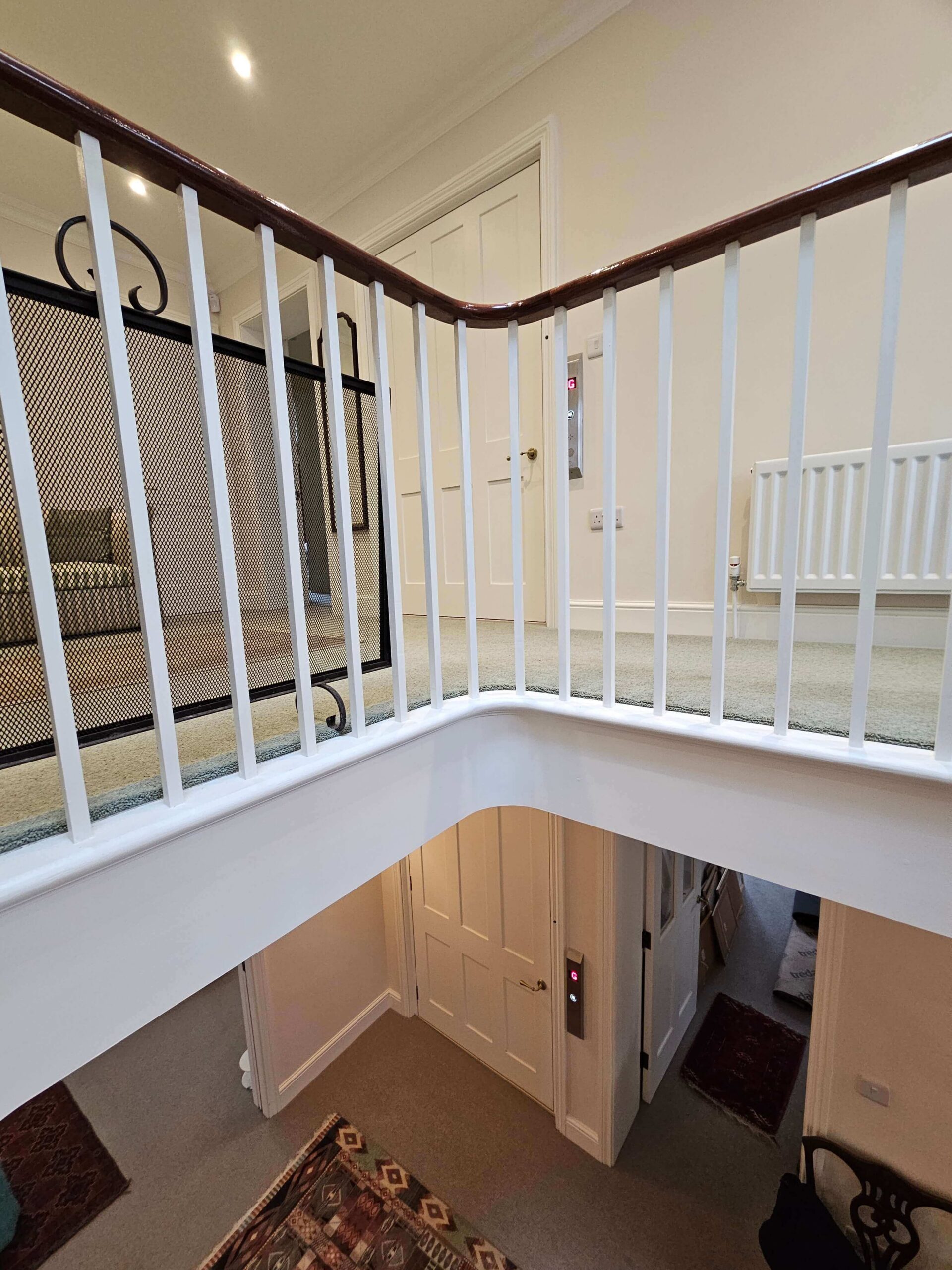 View from the second floor staircase showing the British Style home lift call panels visible on both the ground floor and first floor landings