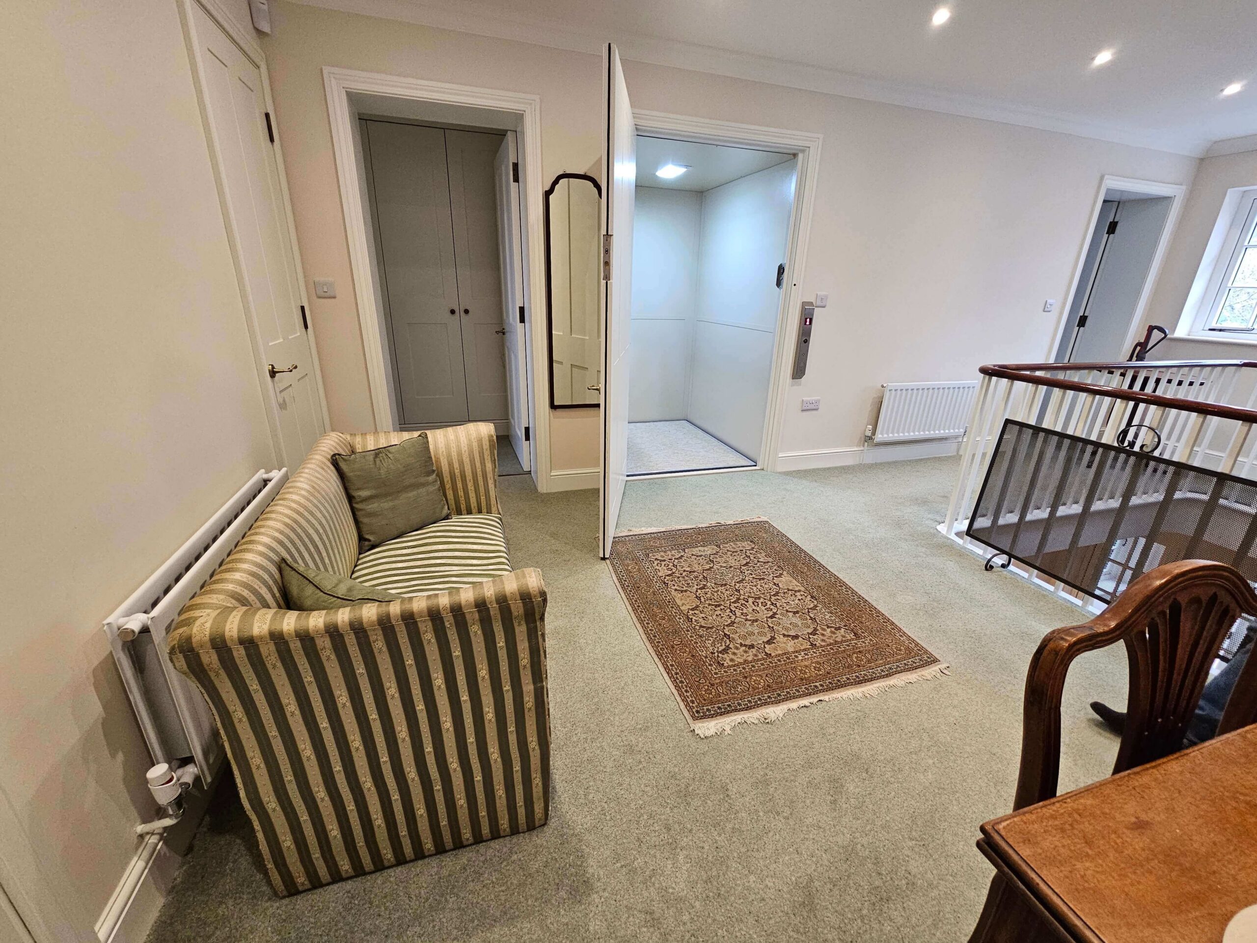 First floor landing with the British Style vertical platform lift doors open, showing the bespoke interior.