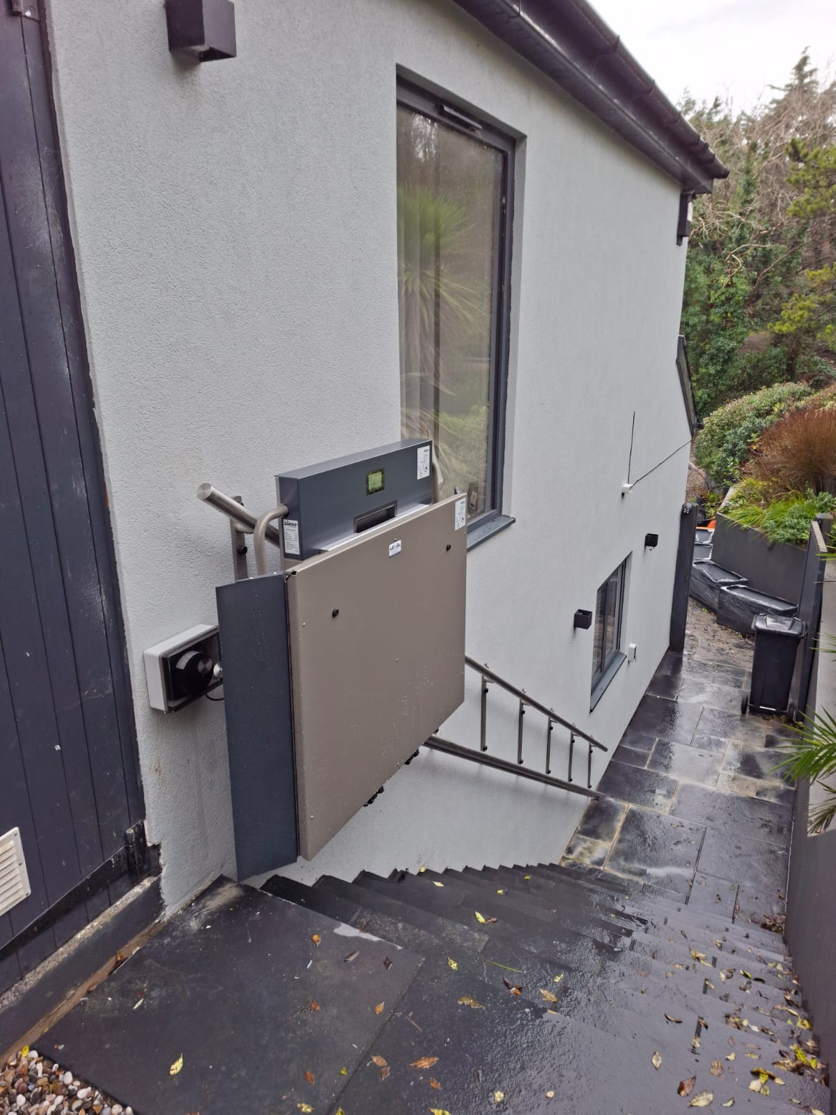 Platform stairlift folded up at the top of a flight of external steps