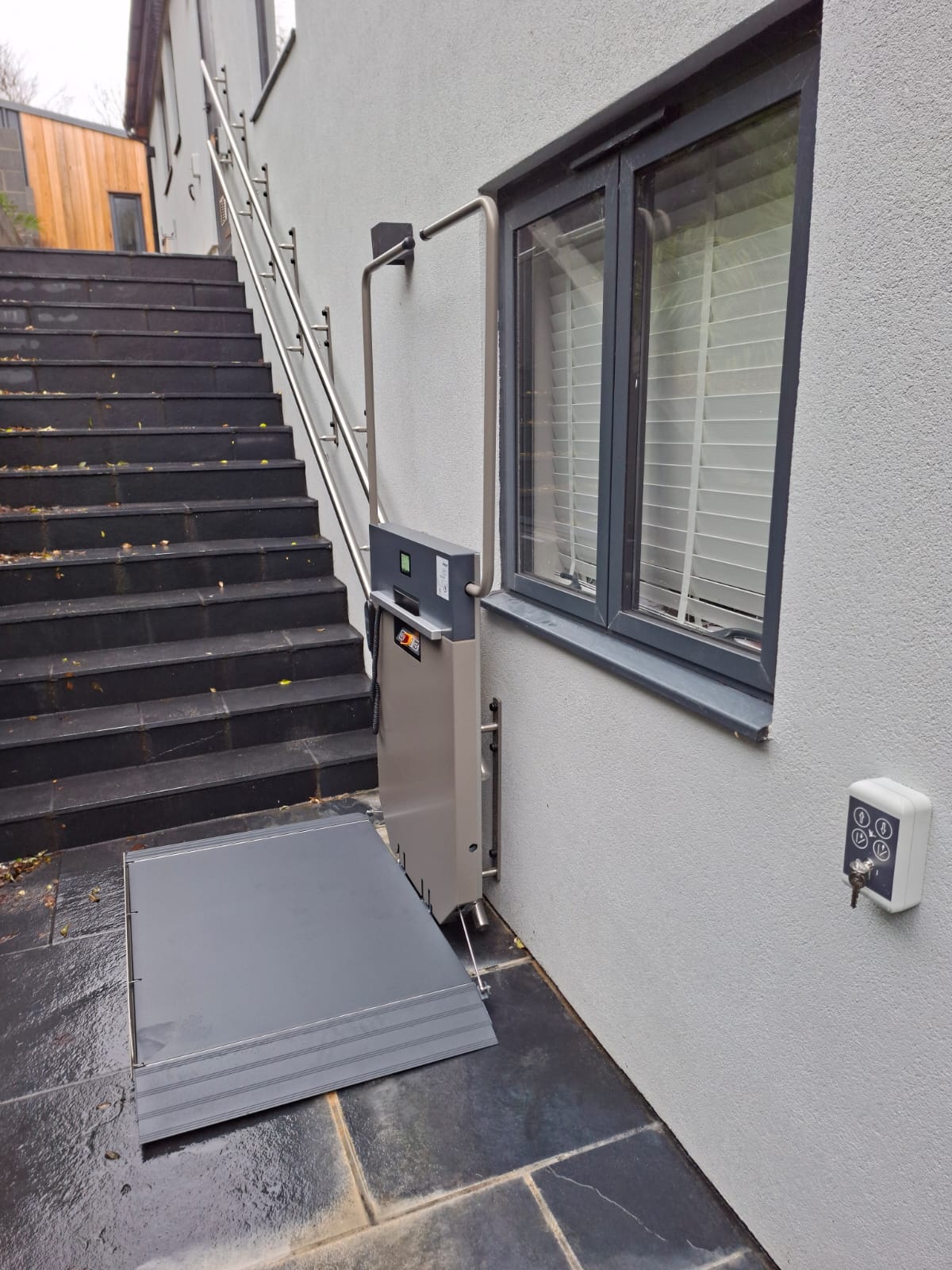 A platform stairlift at the bottom of a flight of external steps
