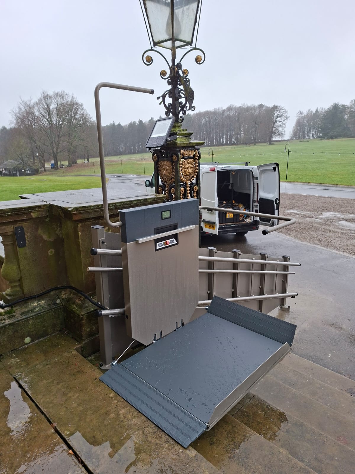 Level Access Lifts GTLE platform stairlift at the top of the entrance steps at Harewood House, view from upper landing looking out across the grounds