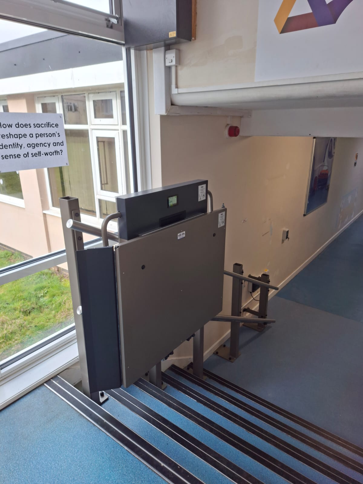 GTLE inclined platform stair lift installed at top of staircase at Filey Academy, viewed from upper level.