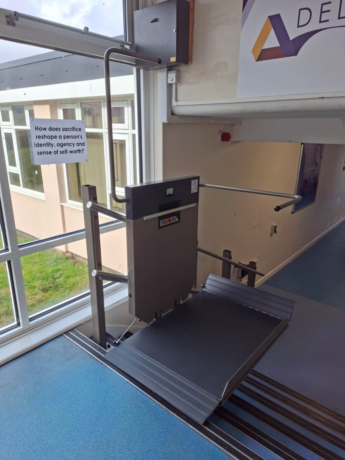 GTLE platform stair lift with platform extended, providing wheelchair access on school corridor steps.
