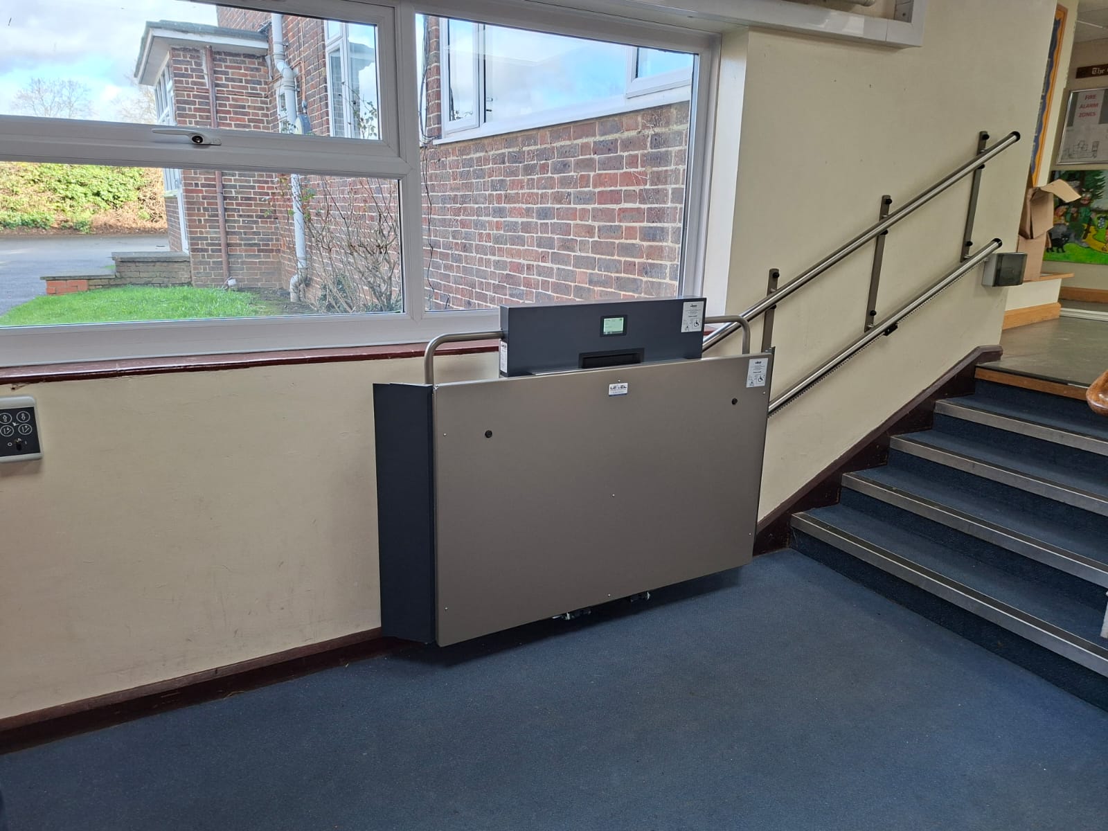 GTLE platform stair lift stowed in lower corridor position at Laurel Lane Primary School, Middlesex