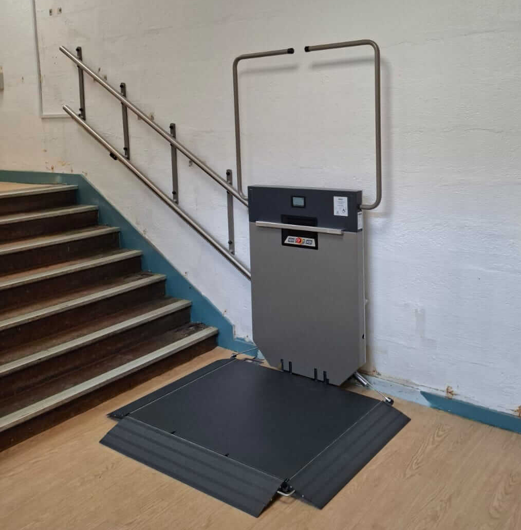GTLE platform stair lift with platform deployed at lower landing, Saltash Community School corridor, Cornwall.