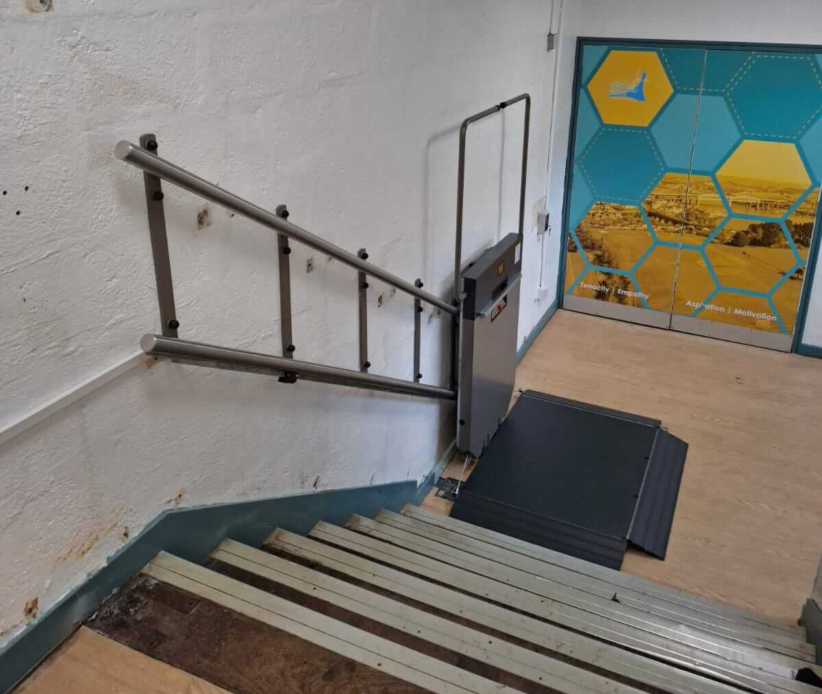 View from upper landing of installed GTLE platform stair lift with deployed platform, Saltash Community School RE department.