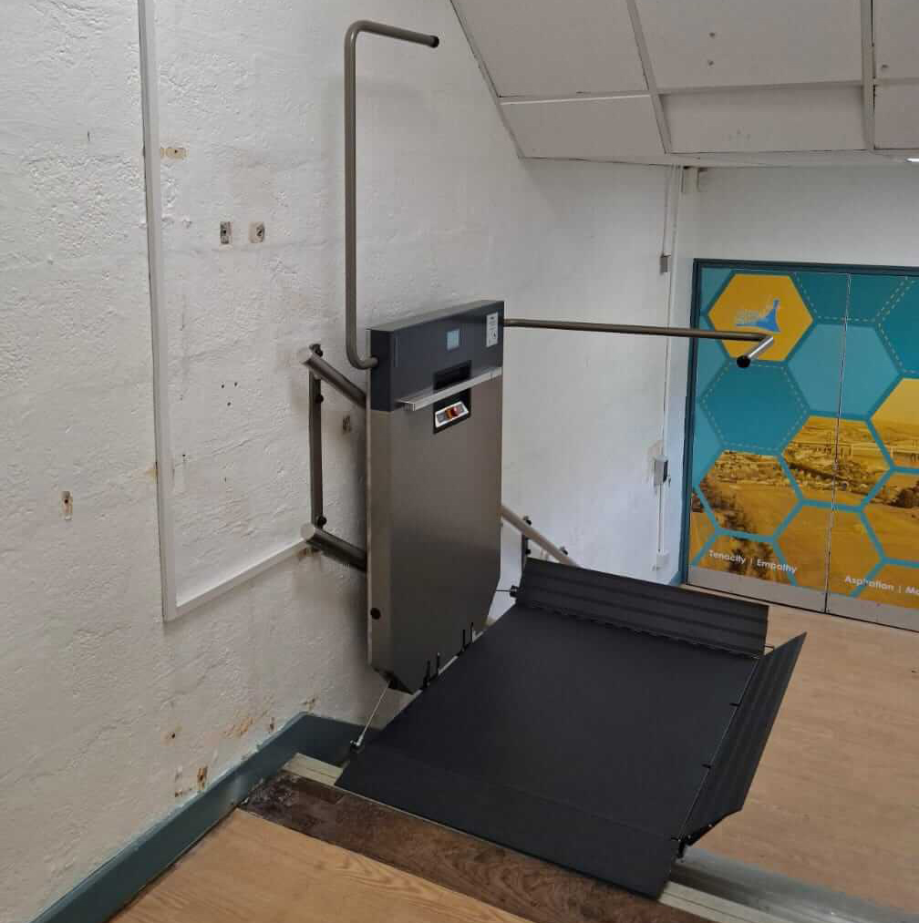 Wall-mounted GTLE platform stair lift with platform deployed at upper landing, Saltash Community School, Cornwall.