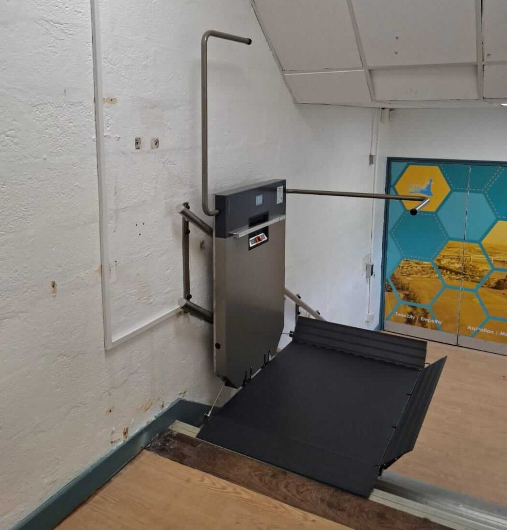 Wall-mounted GTLE platform stair lift with platform deployed at upper landing, Saltash Community School, Cornwall.