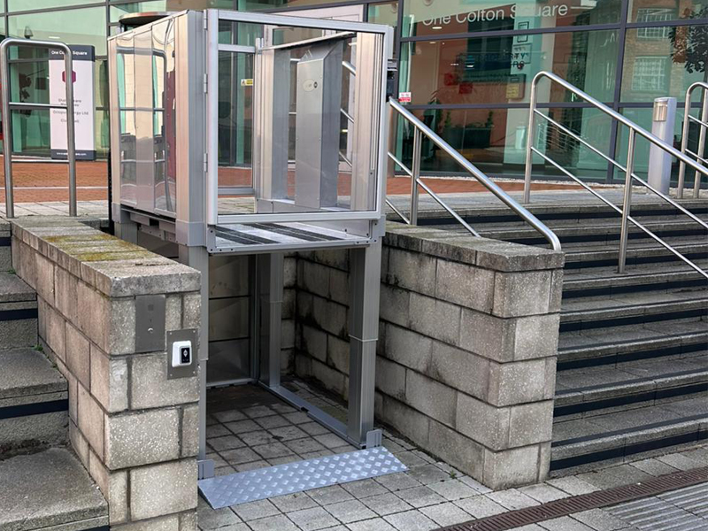 Tech Lift M4 external step lift at upper level at Colton Square, Leicester, with glazed panels and chequer plate ramp.
