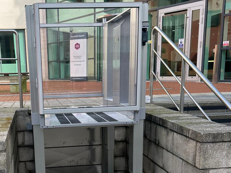 Tech Lift M4 external step lift in raised position at Colton Square, Leicester, with the building entrance and signage visible behind and steps with handrail to the right