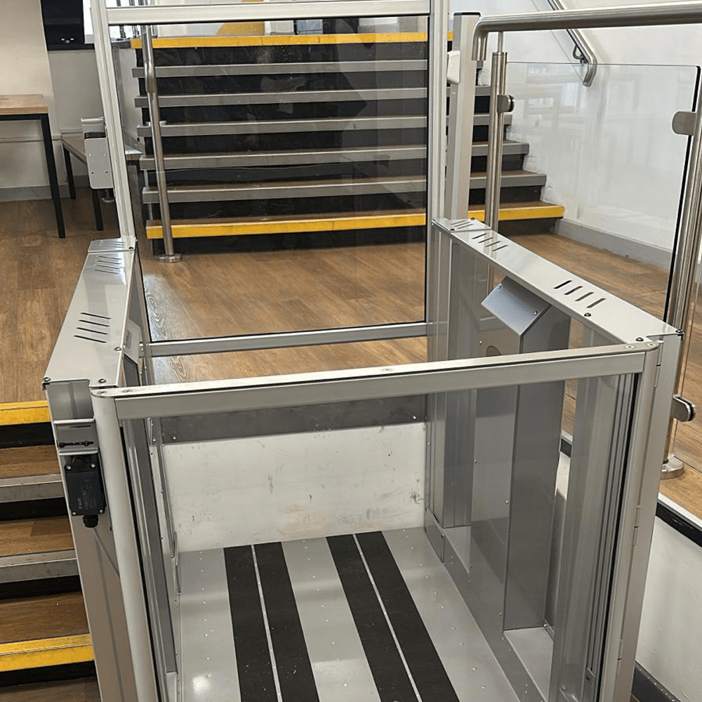 Tech Lift M4 step lift lowered beside the staircase at Stamford College, with the upper refectory seating in the background.